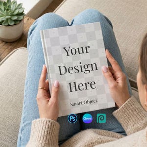 May include: A person holding a notebook with the text "Your Design Here" on the cover. The notebook has a grid pattern and the words "Smart Object" are below the text. The notebook is held over a pair of blue jeans.