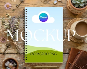 May include: A spiral-bound notebook mockup with a Canva logo on the cover, featuring a blue sky and green landscape design. The image includes decorative elements like keys, flowers, and a cup of coffee, set on a rustic wooden surface. The text "MOCKUP" and "3200x3200 PNG" are also visible.