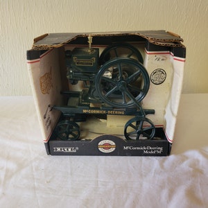May include: A green McCormick-Deering Model "M" vintage engine model in its original box. The model features large wheels and detailed engine components. The box has a black and white design with the text "Vintage Engines".