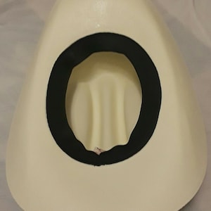 May include: The inside of a white cowboy hat with a black band around the crown.