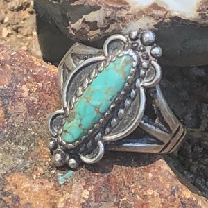 May include: A silver ring with a turquoise stone set in a detailed design. The stone is a light blue-green color with brown veins.