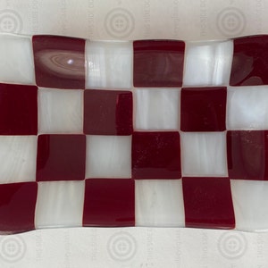 May include: A small, rectangular dish made of glass with a checkerboard pattern in white and burgundy.