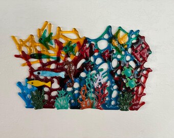 May include: A colorful, handcrafted ocean-themed wall art piece. The artwork features a vibrant coral reef with fish, seahorses, and turtles. The colors include yellow, blue, green, red, and orange, creating a lively underwater scene.