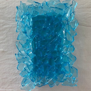 May include: A blue glass phone case made of many small pieces of glass. The case is designed to look like broken glass.
