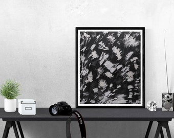 May include: Black and white abstract painting in a black frame on a black table with a potted plant, a camera, a box, a skull, and a radio.