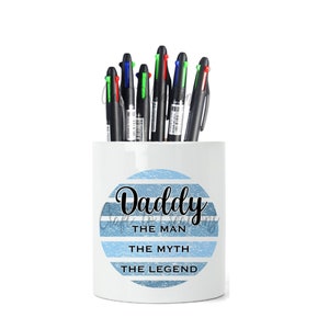May include: White ceramic pencil holder with a blue and white striped design. The holder has the text "Daddy The Man The Myth The Legend" printed on it.