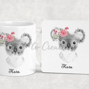 May include: A white ceramic mug and coaster set featuring a grey koala wearing a pink floral crown. The mug and coaster both have the name "Kala" printed on them.