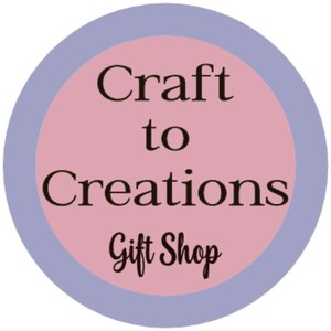 May include: A pink circle with a blue border, the text "Craft to Creations Gift Shop" in black.