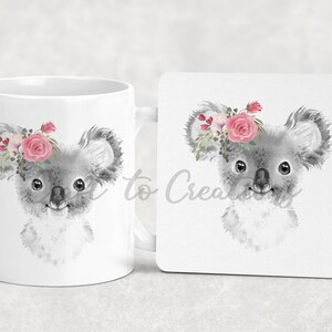 May include: A white ceramic mug featuring a grey koala wearing a pink flower crown. The koala is looking to the right. The mug is accompanied by a matching coaster.