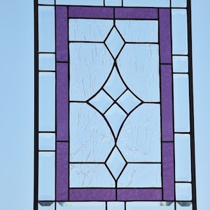 May include: A stained glass window with a diamond pattern in the center. The window is framed in black and has a purple border.