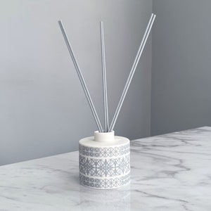 May include: A white ceramic diffuser bottle with a grey geometric pattern and three grey diffuser sticks.