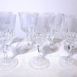 May include: A set of six clear glass goblets featuring a faceted diamond-cut pattern on the lower portion of the bowl and a multi-faceted stem. Each glass has a wide rim and a circular base, reflecting light through the textured glass surface.