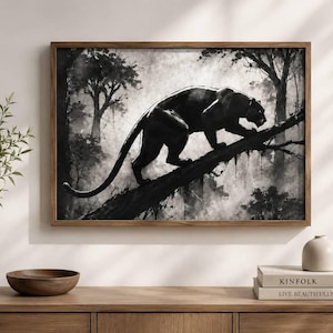 May include: A rectangular wall art print in a wooden frame featuring a black and white illustration of a panther walking along a thick tree branch in a dense forest. The artwork uses high-contrast shading to depict the animal and the misty woods.