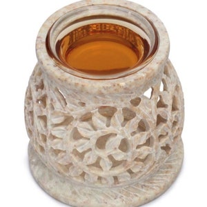 May include: A white stone oil diffuser with a carved floral design. The diffuser has a glass bowl for essential oils and a small opening for a tea light.