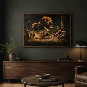 May include: A rectangular framed wall art print depicting a dramatic scene of a lion leaping towards a group of figures in a dark, atmospheric setting. The artwork features warm golden tones on the lion contrasted against deep shadows and earthy browns.