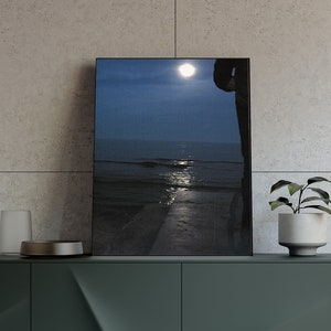 May include: A dark green modern sideboard with gold legs, featuring a framed seascape print, a small potted plant, and a decorative lamp. The cabinet has four doors with geometric detailing, and is set against a neutral tiled wall.
