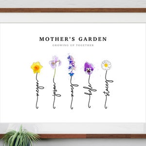 Mother's Garden personalized birth flower print in a wood frame with white mat, leaning on a shelf beside a plant. Five watercolor birth month flowers (daffodil, iris, larkspur, violet and daisy) grow from hand-lettered stems that spell each name. Custom family birth flower art, also made as Grandma's Garden for a sentimental grandma gift.