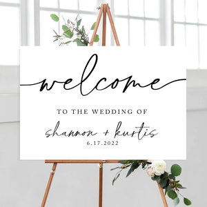 May include: White wedding welcome sign with black calligraphy text that reads "welcome to the wedding of shannon + kurtis 6.17.2022"