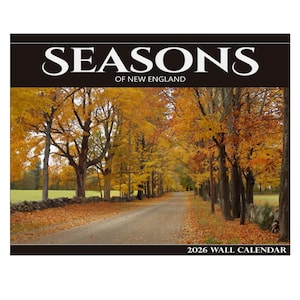 Puede incluir: Un calendario de pared de 2026 con una escena otoñal de Nueva Inglaterra. La imagen muestra una carretera bordeada de árboles con hojas amarillas y naranjas. El título "SEASONS OF NEW ENGLAND" está en la parte superior.