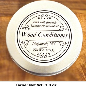 May include: A round silver metal tin of wood conditioner with a white label. The label text reads: made with food-safe beeswax & mineral oil, Wood Conditioner, Napanoch, NY, Net Wt. 3.0 Oz. The container is circular with a flat lid and black text.