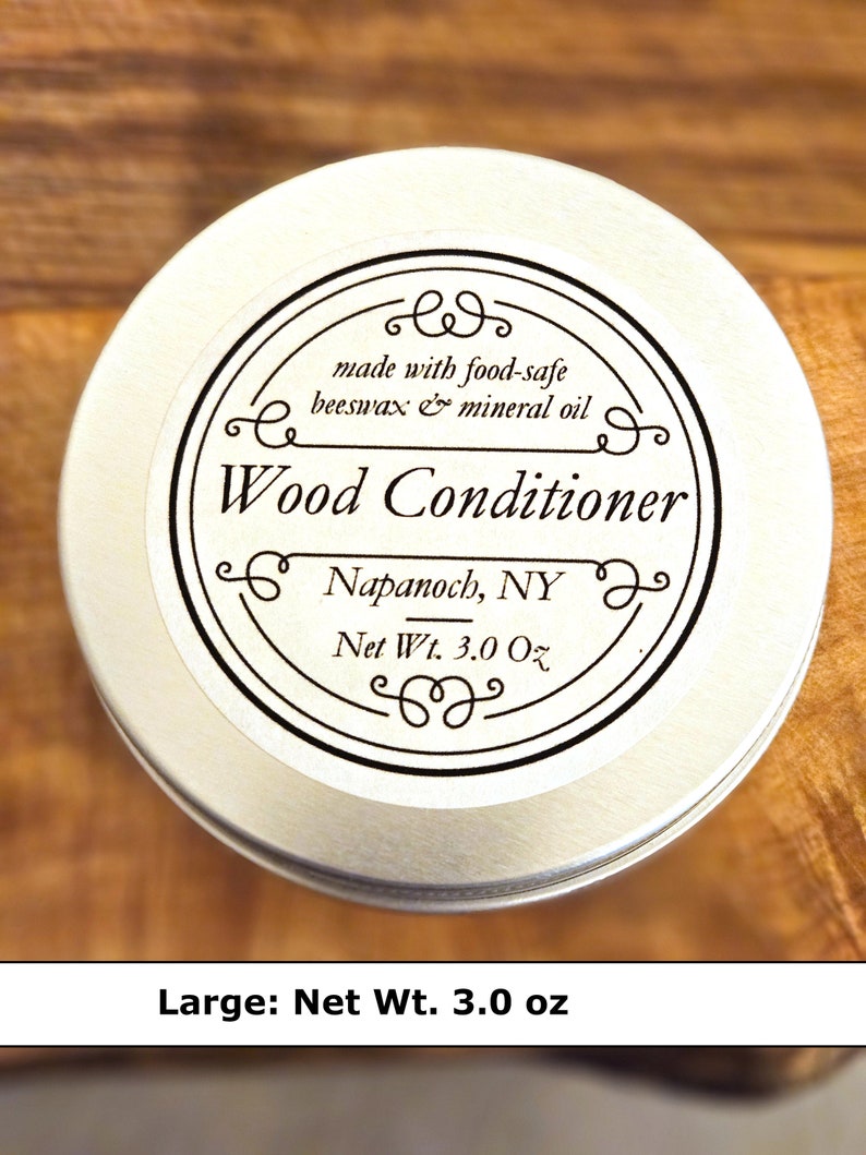 May include: A round silver metal tin of wood conditioner with a white label. The label text reads: made with food-safe beeswax & mineral oil, Wood Conditioner, Napanoch, NY, Net Wt. 3.0 Oz. The container is circular with a flat lid and black text.