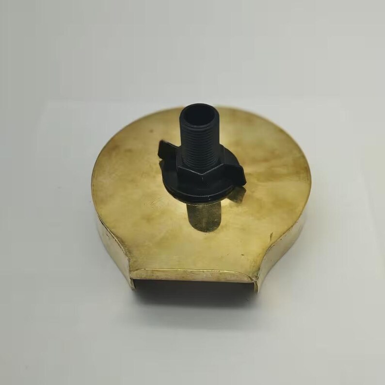 May include: A gold-colored metal shower head with a black plastic connector. The shower head has a unique shape with a curved edge.