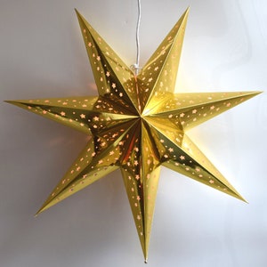 May include: A gold paper star lantern with a white cord hanging from the top. The star has a cut-out design of smaller stars.