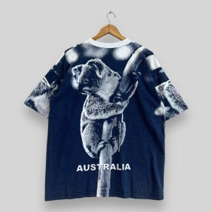 May include: A navy blue t-shirt with a white koala bear print on a tree branch. The shirt has the word "AUSTRALIA" printed in white at the bottom.