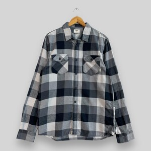 May include: A black and gray plaid long-sleeved button-up shirt with two chest pockets. The shirt has a Vans logo on the left pocket.