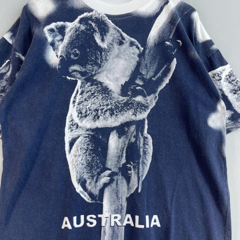 May include: A navy blue t-shirt with a white koala bear graphic and the word "AUSTRALIA" printed on the bottom.