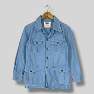 May include: A light blue denim jacket with a button-up front and multiple pockets. The jacket has a "BIG JOHN" label on the left chest.