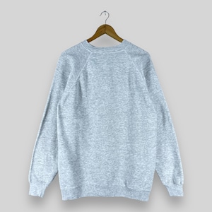 May include: A heather grey sweatshirt with a crew neck and long sleeves. The sweatshirt has a raglan sleeve design.