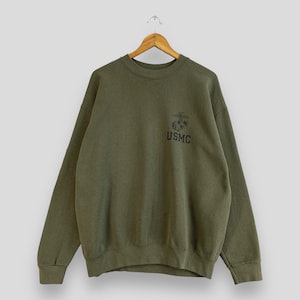 May include: A green sweatshirt with a black USMC logo and the Marine Corps emblem on the front.