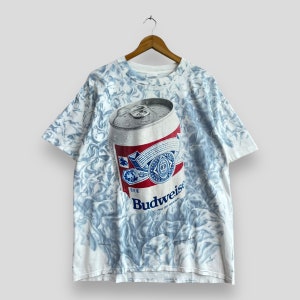 May include: A white t-shirt with a tie-dye pattern featuring a large image of a Budweiser beer can. The can is silver with a red, white, and blue label. The text "Budweiser" is printed on the label.