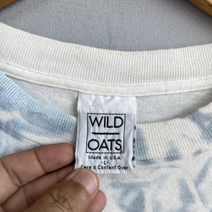 May include: White t-shirt with a blue and white tie-dye pattern. The tag says "WILD OATS" and "Made in U.S.A."