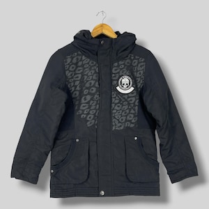 May include: A black hooded jacket featuring a dark gray leopard print pattern on the upper chest panels. The jacket includes a circular patch on the left chest displaying a skull graphic with the text "PSYCHO BUNNY" and "EST. 2005".