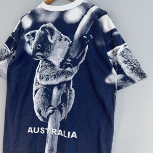 May include: A navy blue t-shirt with a white koala bear graphic. The koala is climbing a tree and the shirt says "AUSTRALIA" at the bottom.