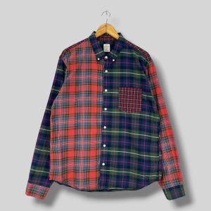 May include: A long-sleeved button-down shirt with a unique plaid design. The shirt is split vertically, with a red and blue plaid on the left and a green and blue plaid on the right. A small plaid pocket is on the left side.