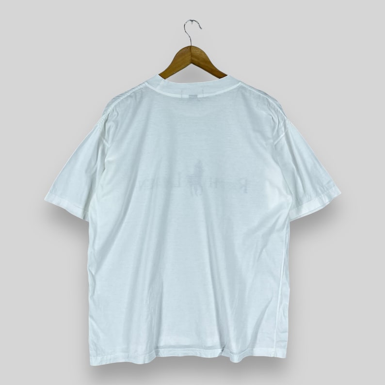 Puede incluir: Camiseta blanca de manga corta con un peque&ntilde;o logotipo descolorido en la parte delantera.