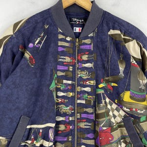 May include: A navy blue bomber jacket with a colorful, all-over print featuring a variety of whimsical designs, including horses, riders, and other abstract patterns. The jacket has a zipper closure and a ribbed collar.