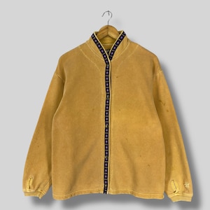 May include: A mustard yellow zip-up sweatshirt with a black and purple patterned trim around the collar and down the front.