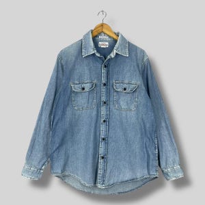 May include: A light blue denim long-sleeve shirt with a button-down collar and two chest pockets. The shirt has a faded look and is made of a soft, comfortable fabric.