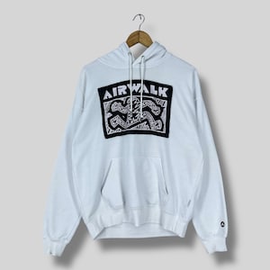 Op de afbeelding: Witte hoodie met een zwart-wit Airwalk-logo op de voorkant. De hoodie heeft een kangoeroezak en een capuchon met trekkoord. Het Airwalk-logo heeft een gestileerd grafisch ontwerp.