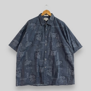 Op de afbeelding: Een blauw, kort mouwig overhemd met knopen en een tropische print. Het overhemd heeft een witte kraag en een zak aan de linkerkant.
