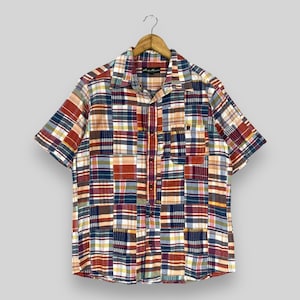 Op de afbeelding: Een kort mouw overhemd met knopen en een patchwork ruitpatroon in tinten rood, blauw en beige. Het overhemd heeft een knoopsluiting en een borstzak.