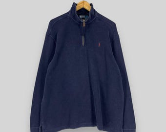 May include: A navy blue quarter-zip pullover sweater with a small embroidered polo player logo on the left chest. The sweater has a ribbed collar and cuffs.