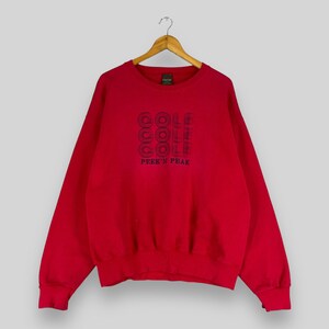 May include: Red sweatshirt with a navy blue embroidered logo that says "COOL" four times and "PEEK'N PEAK" underneath.