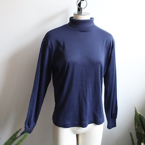 以下が含まれることがあります： 白いマネキンに着せられた、ネイビーブルーのロングスリーブタートルネックセーター