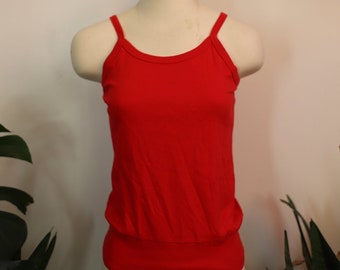 May include: A red sleeveless tank top with a scoop neck and a fitted, banded bottom.
