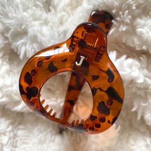 May include: A brown and black tortoiseshell hair claw with a letter J on the front.